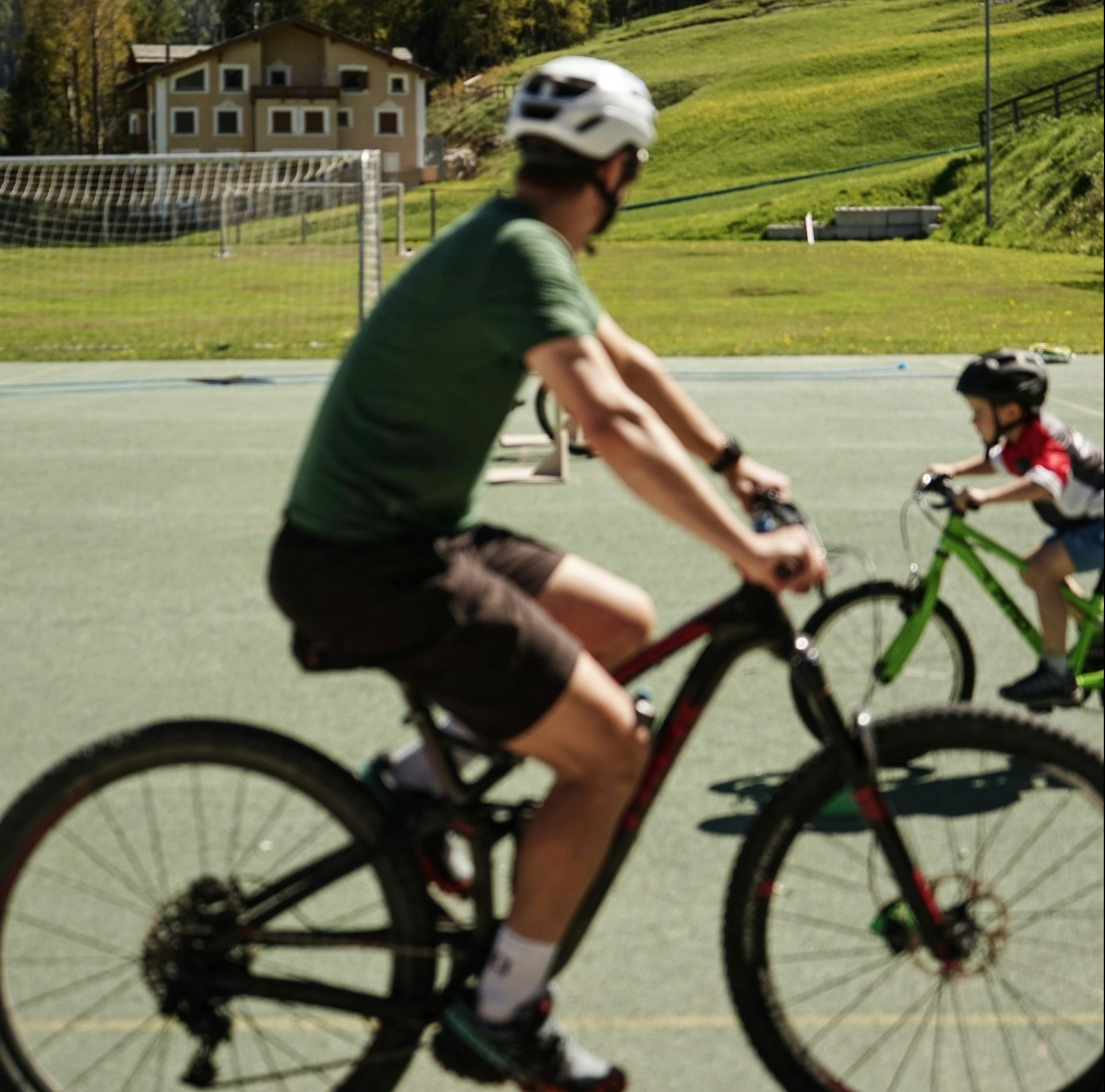 Cyclists are riding on a paved area near a mountain.